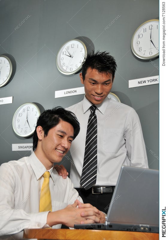 Asian Business Executives In Room Full Of Clocks Stock Photo