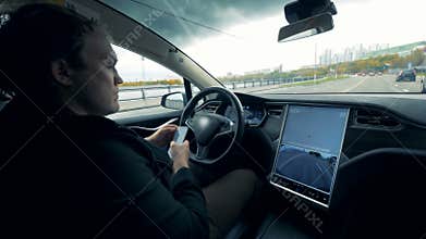 Driver is browsing his phone while the car is moving along the road