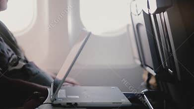 Close-up side view of plane passenger watching videos on mobile tablet video player device, moving it closer to himself.