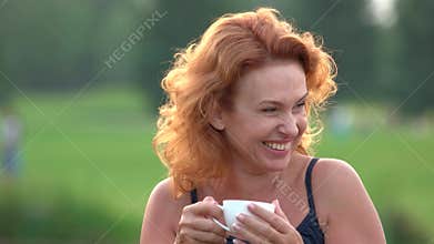 Happy smiling woman drinking tea outdoors.