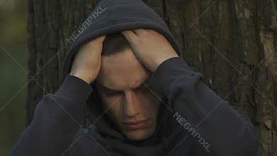 Frustrated teen hiding in park, suffering from bullying, communication problems