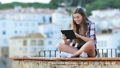 Happy teen using a tablet on vacation