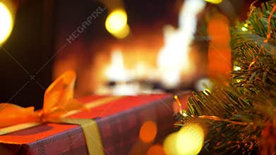 Christmas red gift box. Christmas three on glow fireplace bokeh lights background