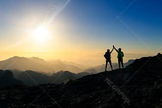 Couple hikers celebrating success concept in mountains