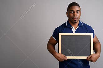 Young handsome African man wearing blue polo shirt against gray