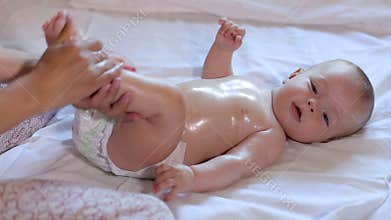 Mother makes newborn baby massage, apply oil on the body, on white background.