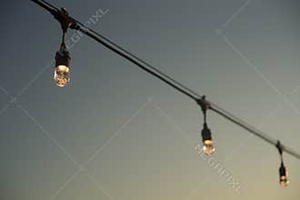 String of three bulb lights in front of the sky