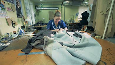 Seamstress is sewing fur coats in a workshop