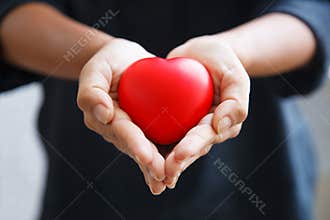Red heart held by female`s both hands, represent helping hands, caring, love, sympathy, condolence, customer relationship, patient
