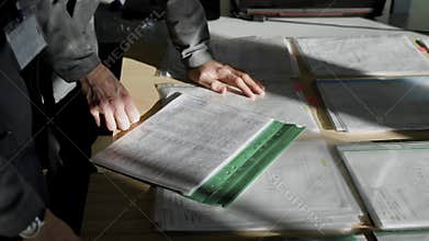 Engineers in the company are discussing the drawings of the new parts. Drawings are printed on the printer for workers.