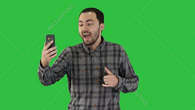 Young blogger recording video on his phone while walking on a Green Screen, Chroma Key.