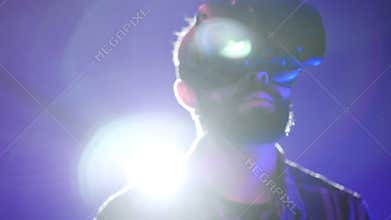 Close-up portrait of bearded man uses VR-headset display for virtual reality video game in vr club. Looking around