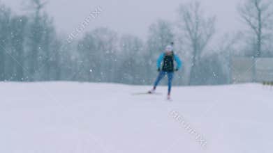 Stadium during snowfall with a sportswoman skiing through it