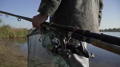 A man carries fishing rods and fish nets close up. Slow motion.