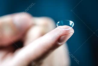 Contact lenses macro close up. Man holding lens on finger.