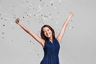 Beautiful happy woman at celebration party with confetti falling everywhere on her. Birthday or New Year eve celebrating concept