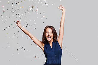 Beautiful happy woman at celebration party with confetti falling everywhere on her. Birthday or New Year eve celebrating concept