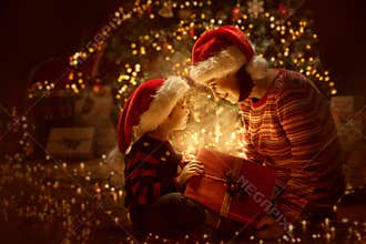 Family open Christmas Lighting Present Gift Box front of Xmas Tree, Happy Mother with Baby