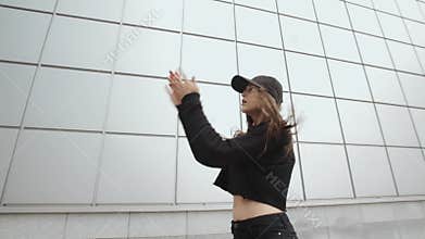Girl dancer in black performs modern hip-hop dance, contemporary freestyle, urban environment