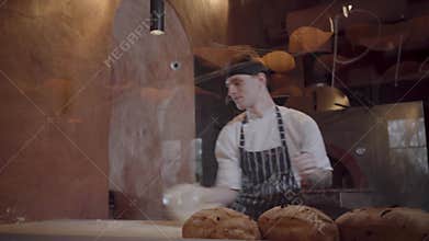 Professional cook spinning and throwing pizza dough up in kitchen of restaurant.