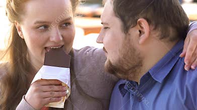 Happy loving couple biting chocolate and nuzzling, high sugar food, tenderness