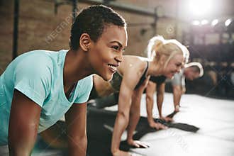 Smiling young woman doing pushups in a gym exercise class