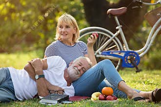 Happy senior couple relaxing in park  together. old people sitting on grass in the summer park . Elderly resting .mature