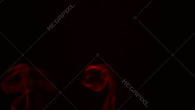 Red smoke from aromatic sticks close up on black background