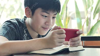 Teenage boy plays games on mobile phone.