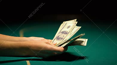Hands counting money on poker table, lucky night, casino winnings, closeup