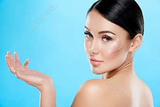 Attractive girl with nude make up and naked shoulders at studio background, invisible eye patches on face, skin care