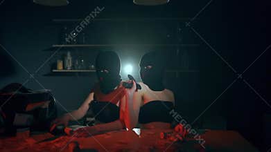 The girls robbers in a black masks and suit with pistols and cash. Bag with money