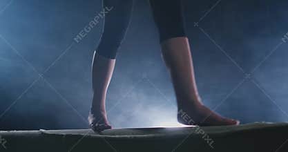 Girl gymnast practicing on a balance beam in gym.