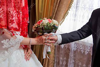 Hands with wedding flowers, groom puts on an wedding flowers to the bride, dressing up an wedding flowers, groom with