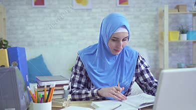 Beautiful young muslim woman in hijab, studying in modern apartments portrait