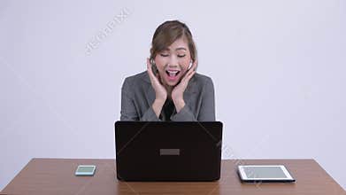 Young happy Asian businesswoman getting good news at work