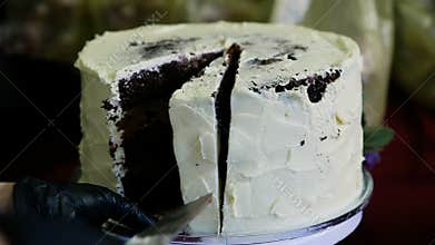 Confectioner hand in black glover cuts big chocolate cake