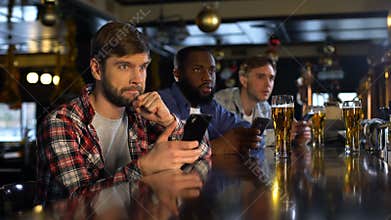 Men monitoring sport bets on cellphone and competition results, bookmaker online