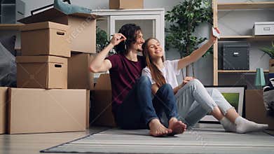 Girl and guy taking selfie with keys in new house using modern smartphone camera