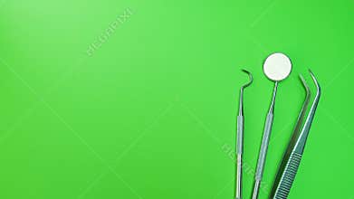 Dentist mirror, forceps curved, explorer curved, dental explorer angular and explorer curved with chip, right at green background