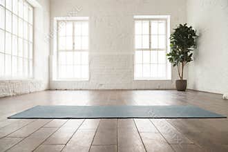 Unrolled yoga mat on wooden floor in yoga studio