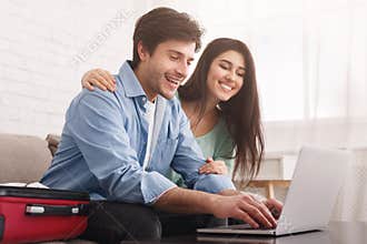 Happy couple planning travel, booking tickets online on laptop