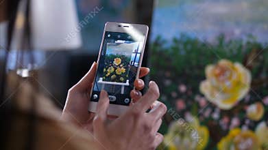 Hands of artist taking smartphone photo of canvas