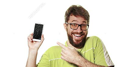 The concept of a broken gadget. A bearded man shows the smartphone with a broken screen. He`s laughing hysterically