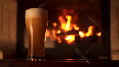 Pouring stream into glass bocal of refreshment beer with foam and air bubbles fireplace slow motion
