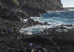 Ponta da Ferraria, Sao Miguel Island, Azores Islands, Portugal December 26, 2018: young womaman trying to climbe down to