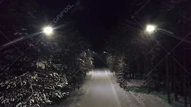 Park path at night in snow. Clip. Top view of mysterious and frightening turning off lights on forest trail plunging