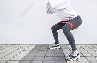Squat with a rubber band on the background of a white wall, close photo. Sports concept