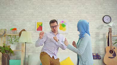 Young man and muslim woman in hijab dancing fun