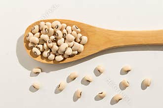 Black Eyed Pea legume. Healthy grains on a wooden spoon. White b